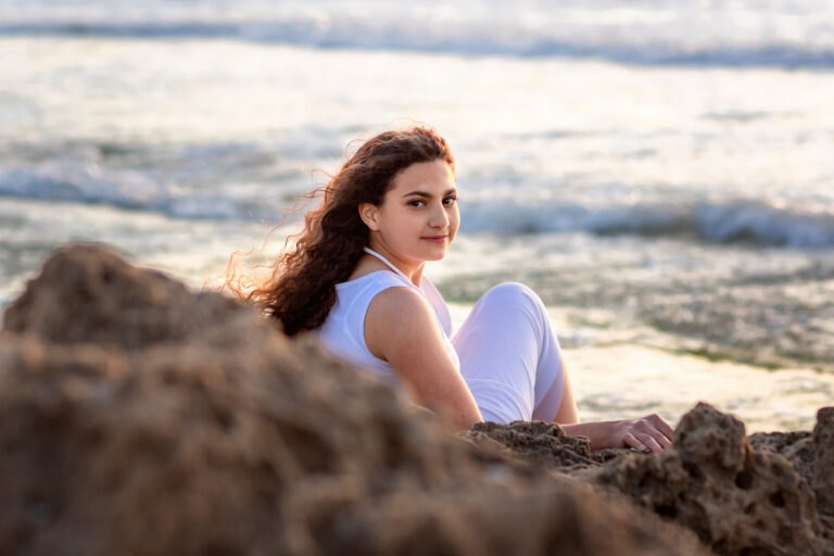 ילדת בת מצווה יושבת בין הסלעים בים- עמליה לוקאש