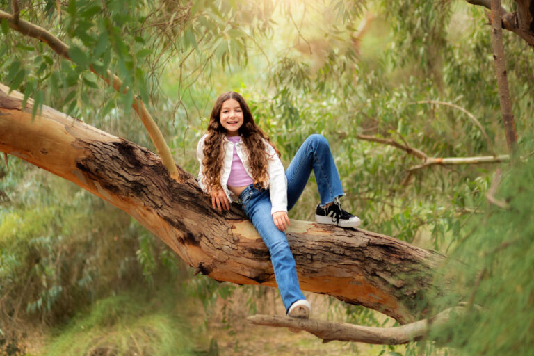 ילדת בת מצווה יושבת על גזע עץ ביער- עמליה לוקאש